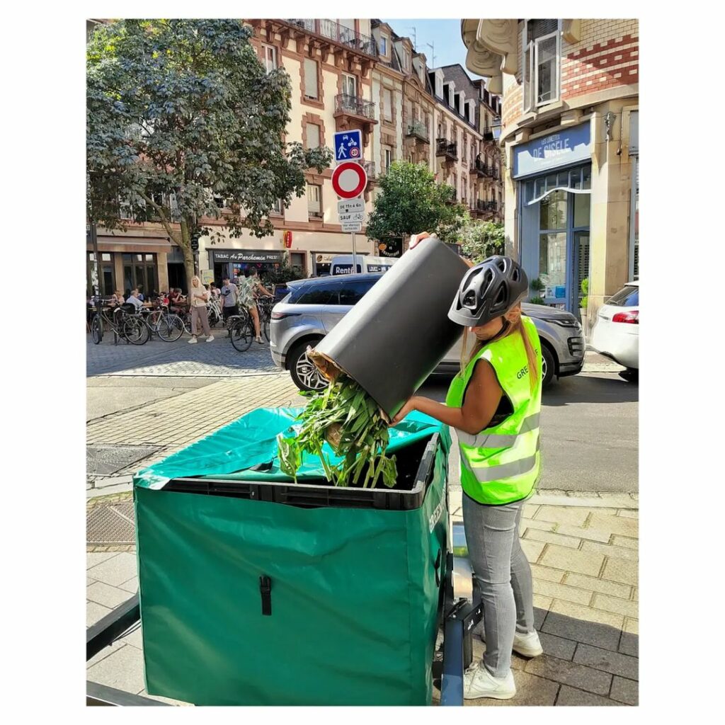 Photo d'une équipière de collecte en train de vider des biodéchets dans un vélo-cargo.